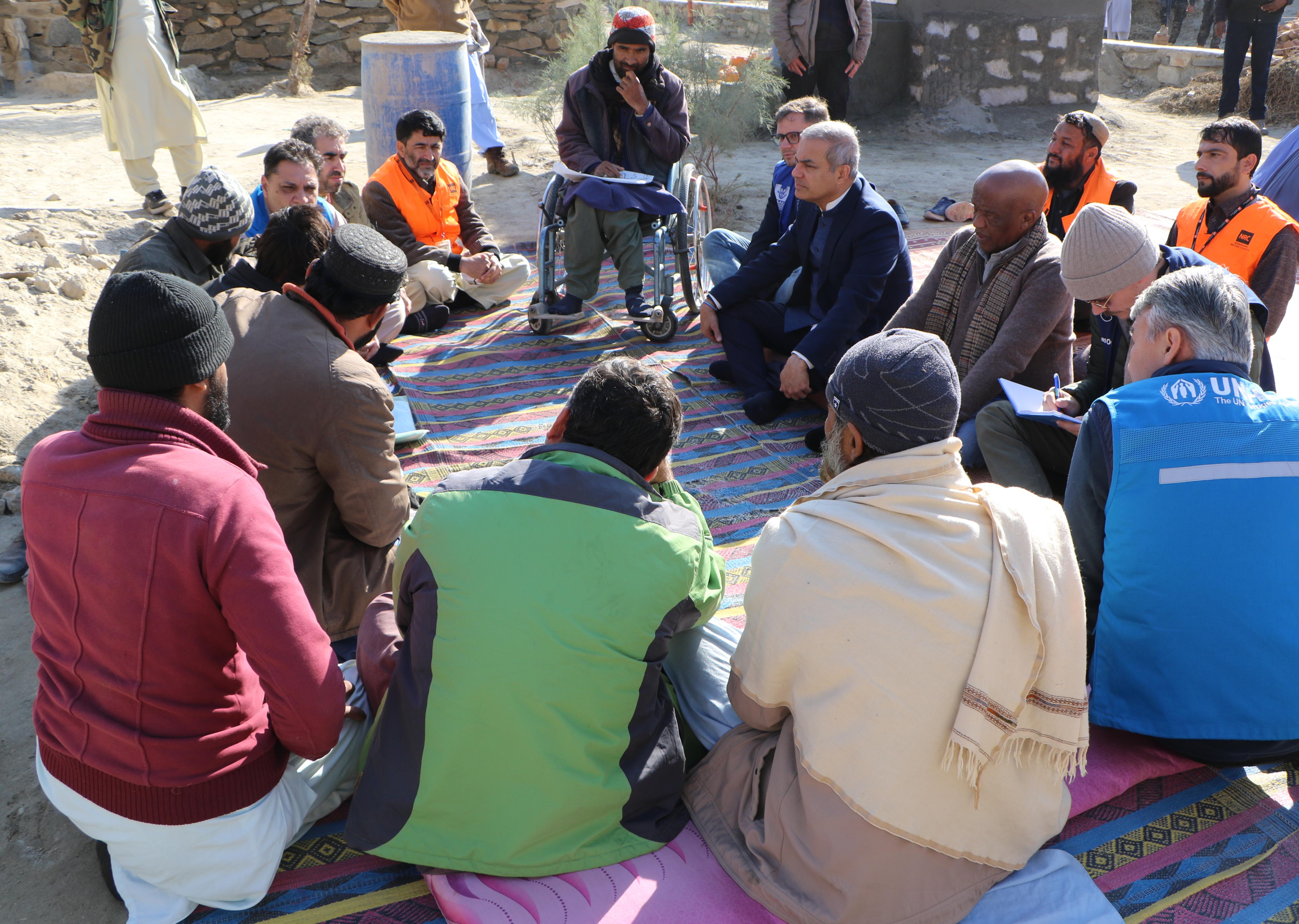 Visit to the Khogyani community resource centers. A group of men sitting in a round on the ground.