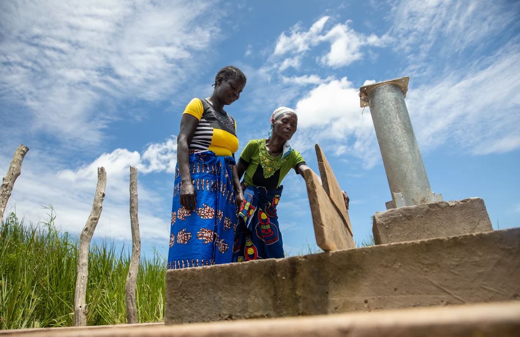 Women check on a water pump